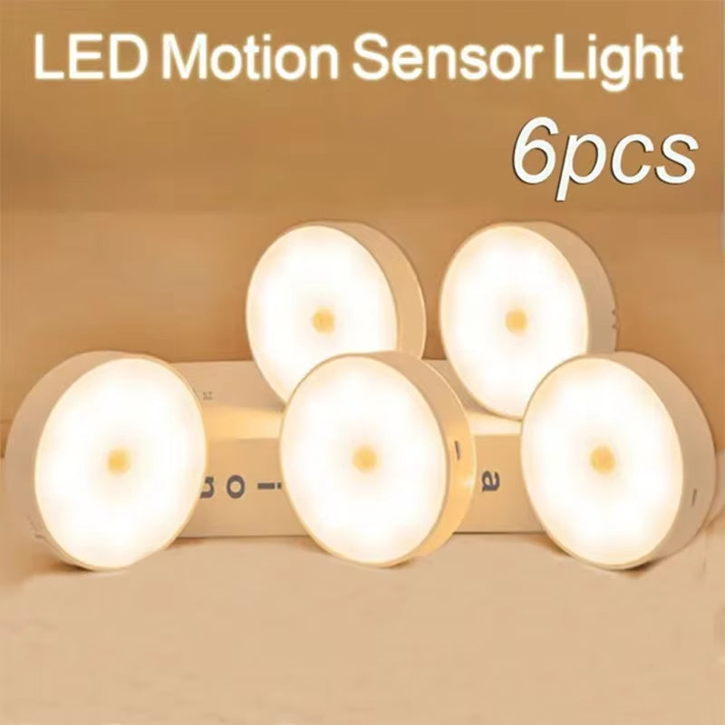 Six-pack of round LED motion sensor night lights glowing warm white, stacked display.